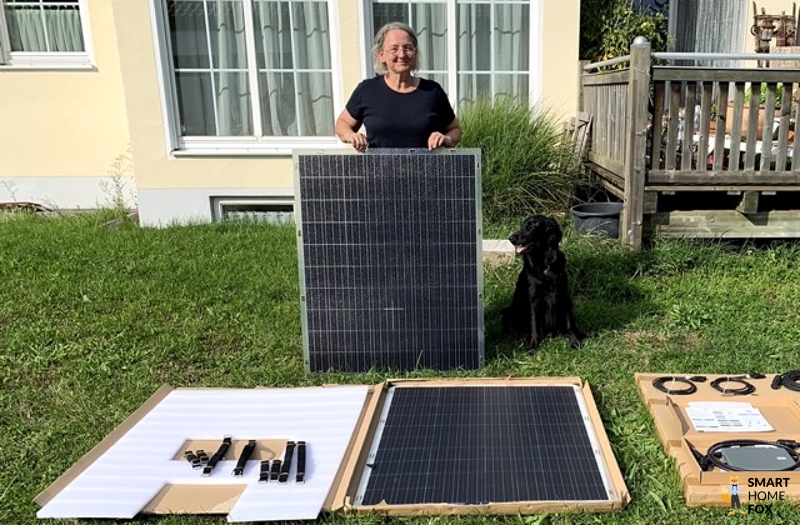 Frau hält Solarmodul fest, davor ein weiteres Modul